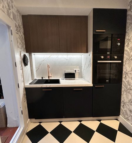 Vista frontal de muebles de cocina negros con iluminacion LED bajo repisa