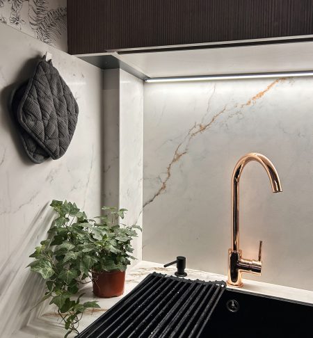 Detalle de griferia dorada y salpicadero de marmol en diseno de cocina